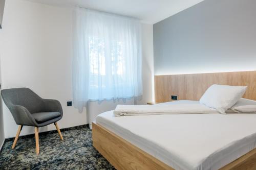 a bedroom with a bed and a chair at Complex Turistic Capus & Spa in Căpuşu Mare