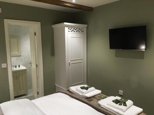 1 Schlafzimmer mit einem Bett mit 2 Handtüchern und einem TV in der Unterkunft Greyhound Inn Wilton in Salisbury