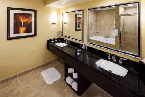 Un baño con dos lavabos y un espejo grande. en Houston Marriott Energy Corridor, en Houston