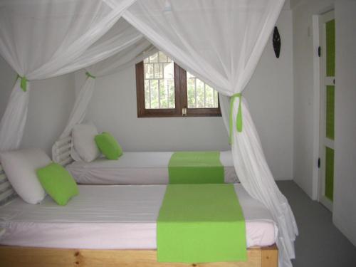 1 dormitorio con 2 camas con sábanas verdes y blancas en Le Jardin de L'isle en Ifaty