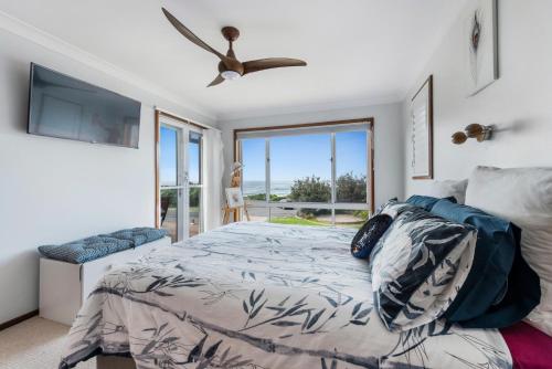 a bedroom with a bed and a ceiling fan at Waterfront and direct beach access with views in Ulladulla