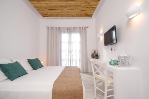 a white bedroom with a bed and a desk at Thomais Studios in Naxos Chora