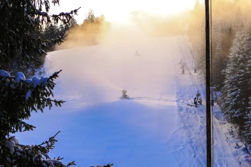 a snow covered ski slope with the sun in the background at Lux Garden Hotel in Azuga