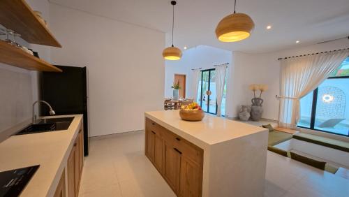 a kitchen with white walls and wooden cabinets and a counter top at Miko Villa Seminyak in Seminyak