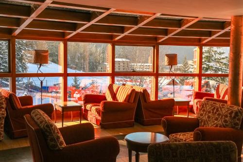 a room with couches and chairs in front of a large window at Lux Garden Hotel in Azuga