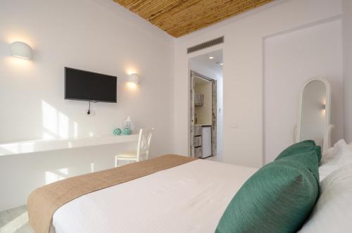 a white bedroom with a bed and a flat screen tv at Thomais Studios in Naxos Chora