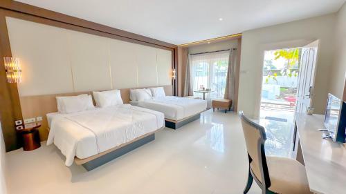 a bedroom with two beds and a desk and a television at Sevilla Resort Magelang in Magelang