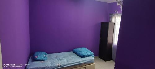 a bedroom with purple walls and a bed with blue pillows at homestay RUSA in Kampong Kerayong