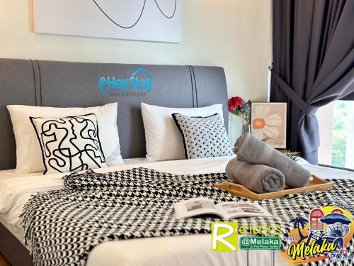 a bed with a tray with a book on it at The Apple Residence By Heystay Management in Melaka