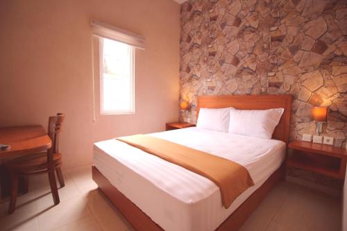 1 dormitorio con cama y pared de piedra en Amaya Suites Hotel en Yogyakarta