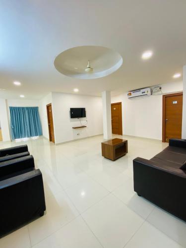 a large living room with black furniture and a flat screen tv at HK Guest Rooms in Guntūr
