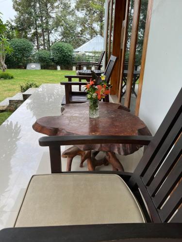 a wooden table with a vase of flowers on a porch at Mandhasativa Homestay in Singaraja