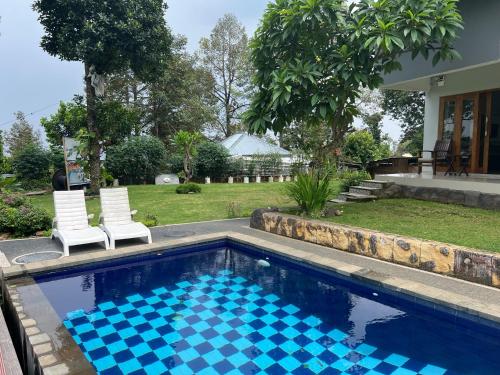 a swimming pool with two chairs and a house at Mandhasativa Homestay in Singaraja