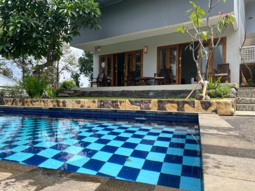 a swimming pool with blue tiles in front of a house at Mandhasativa Homestay in Singaraja
