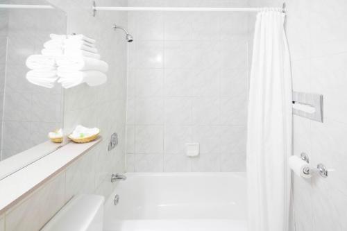 uma casa de banho branca com uma banheira e um chuveiro em Hôtel Marineau Centre em La Tuque