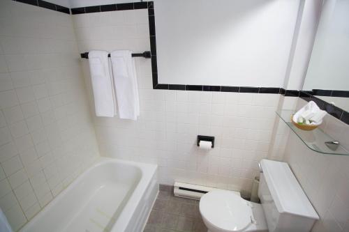 een badkamer met een bad, een toilet en een wastafel bij Hôtel Marineau Mattawin in Trois Rives