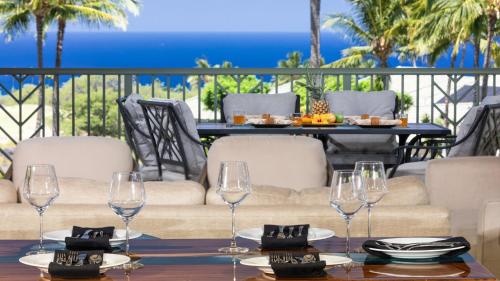 a table with wine glasses on a patio at ❤PiH❤ A Sea-nic Escape Stunning Ocean View Mauna Kea Resort eBikes in Hapuna Beach
