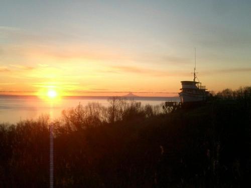 a sunset over the ocean with a lighthouse in the foreground at Alaska Adventure Cabins in Homer