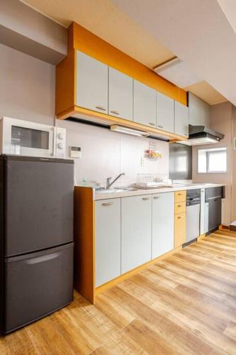 a kitchen with white cabinets and a black refrigerator at UNITED GARDEN hotel 2 in Utsunomiya