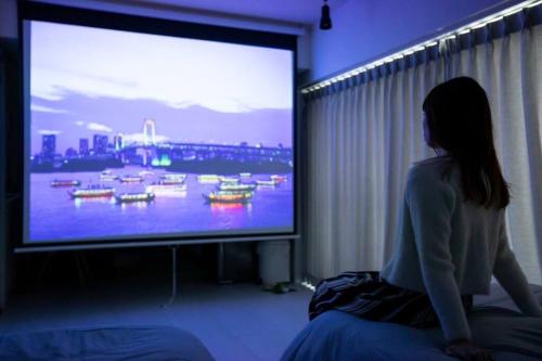 a woman sitting in front of a large screen television at NIYS apartments 55 type in Tokyo