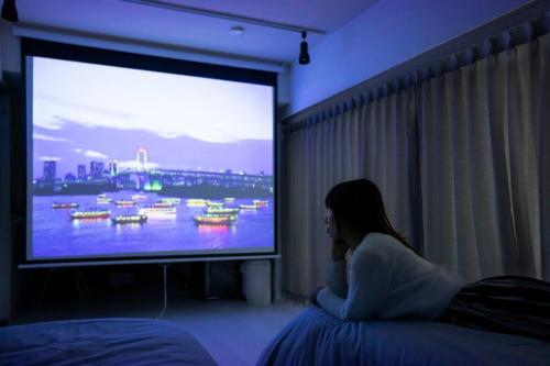 a woman sitting on a couch watching a television at NIYS apartments 55 type in Tokyo