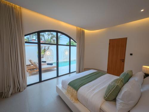 a bedroom with a large bed and a large window at Miko Villa Seminyak in Seminyak