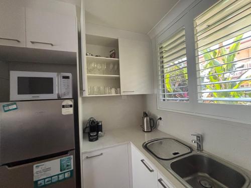a small kitchen with a sink and a microwave at Tropical Ground-Floor Retreat Cairns in Cairns North