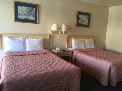 2 letti in una camera d'albergo con coperte rosse di Coastal Motel a Jacksonville