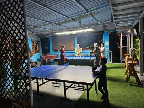 a group of people standing around a ping pong table at Alto Quiel Country in Alto Quiel