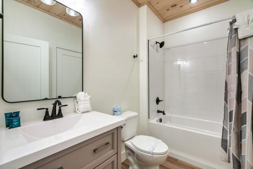 a bathroom with a sink and a toilet and a mirror at New Luxurious 4Bd 5B Ensuite Cabin with Indoor Pool, HotTub, Theater and Game Room, Spring Deal in Sevierville
