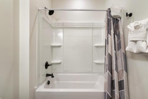 a white bathroom with a tub and a shower at New Luxurious 4Bd 5B Ensuite Cabin with Indoor Pool, HotTub, Theater and Game Room, Spring Deal in Sevierville