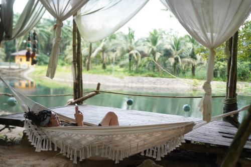 a woman laying in a hammock by a pool at KRABI BAMBOO KINGDOM at AOLUEK PARADISE in Ao Luk