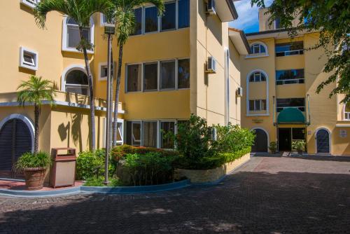 a yellow building with palm trees in front of it at Apartotel & Suites Villas del Rio in San José