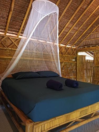 a bed in a thatched room with a mosquito net at Baanchomjan Kohyaoyai in Ban Nai Wat