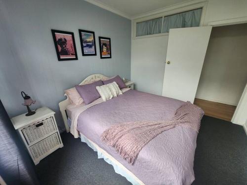 a bedroom with a bed with a purple blanket at Rosebud Retro Retreat in Rosebud