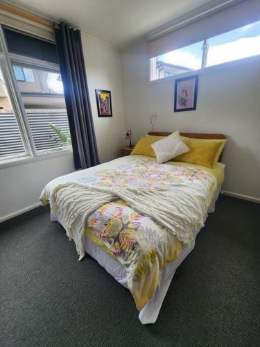a bedroom with a bed with a comforter and two windows at Rosebud Retro Retreat in Rosebud
