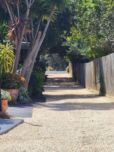 a pathway with a fence and trees and plants at Rosebud Retro Retreat in Rosebud