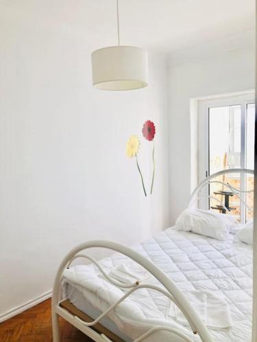 a white bed in a white room with a window at Cantinho de Algés in Algés