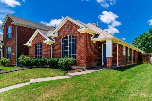 a red brick house with a lawn at Relaxing 3BR 2BA Oasis - Hot Tub & 5 Beds! in The Colony