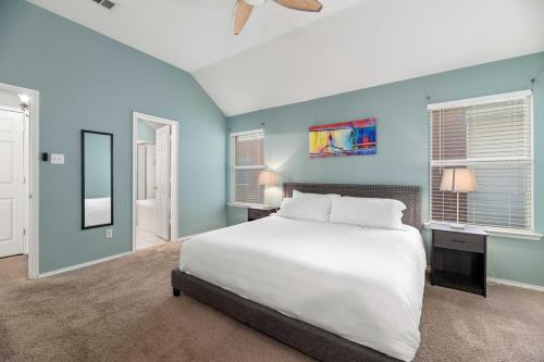 a bedroom with a white bed and blue walls at Relaxing 3BR 2BA Oasis - Hot Tub & 5 Beds! in The Colony