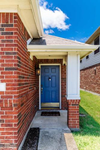a brick house with a blue front door at Relaxing 3BR 2BA Oasis - Hot Tub & 5 Beds! in The Colony