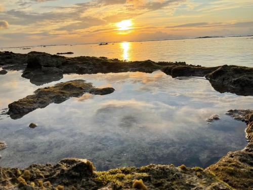 a sunset over the water with rocks at Tepoea Lodge in Fare