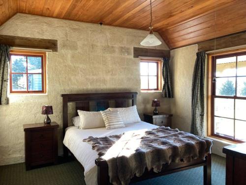 a bedroom with a bed and two windows at Kingfisher cottage in Hurunui