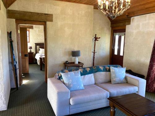 a living room with a white couch and a bedroom at Kingfisher cottage in Hurunui