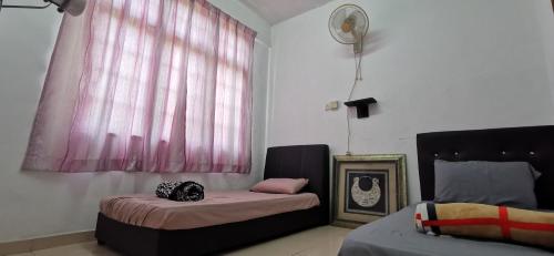 a room with two beds and a window with pink curtains at Anggerik Homestay in Kampong Batang Melekek