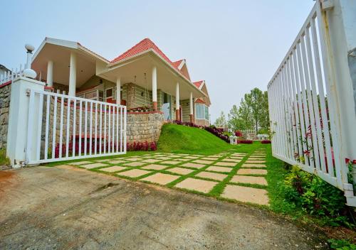 a house with a white fence and a driveway at EMYs Misty Charm Private Villa Ooty by VOYE HOMES in Ooty
