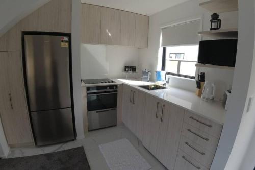 Una cocina con refrigerador de acero inoxidable y ventana. en C-Side-R, Modern Beachfront Living, en Christchurch