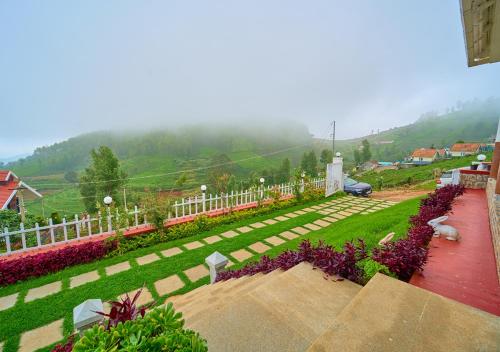 a garden with purple flowers and a white fence at EMYs Misty Charm Private Villa Ooty by VOYE HOMES in Ooty