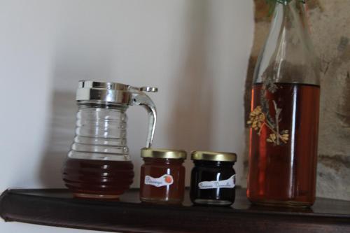 Un estante con tres tarros de miel y una botella. en Quinta de São João, en Poios