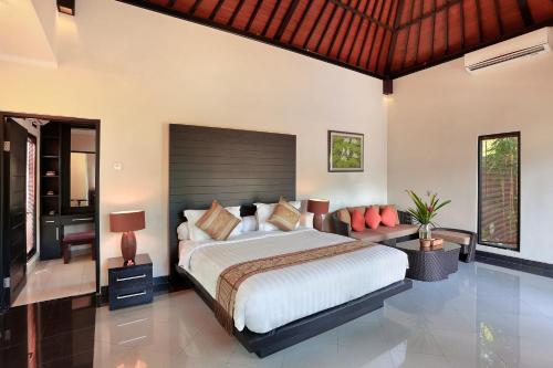 a bedroom with a large bed and a desk at Askara Villa in Canggu